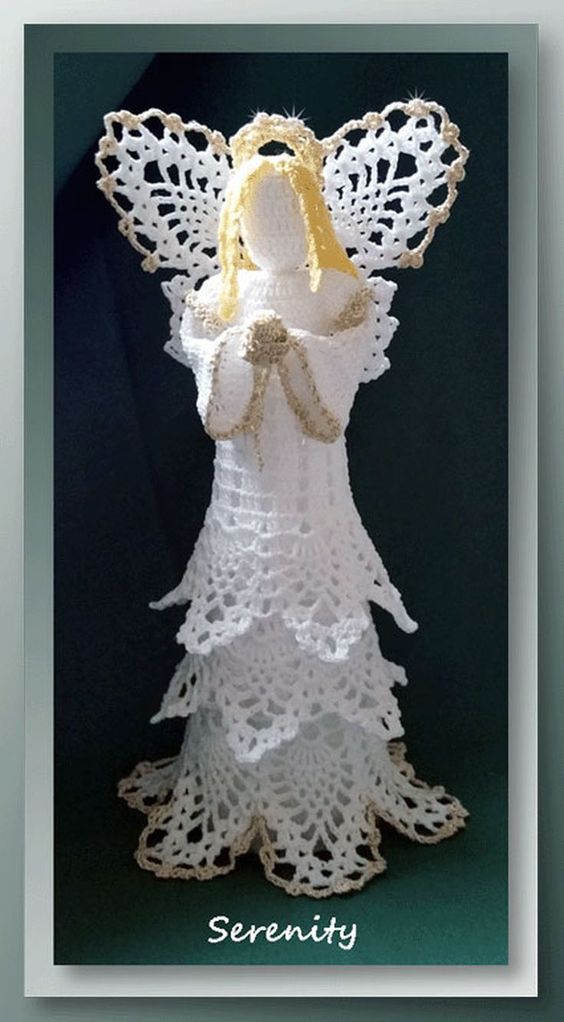 a white crocheted angel with a yellow ribbon on it's chest and wings